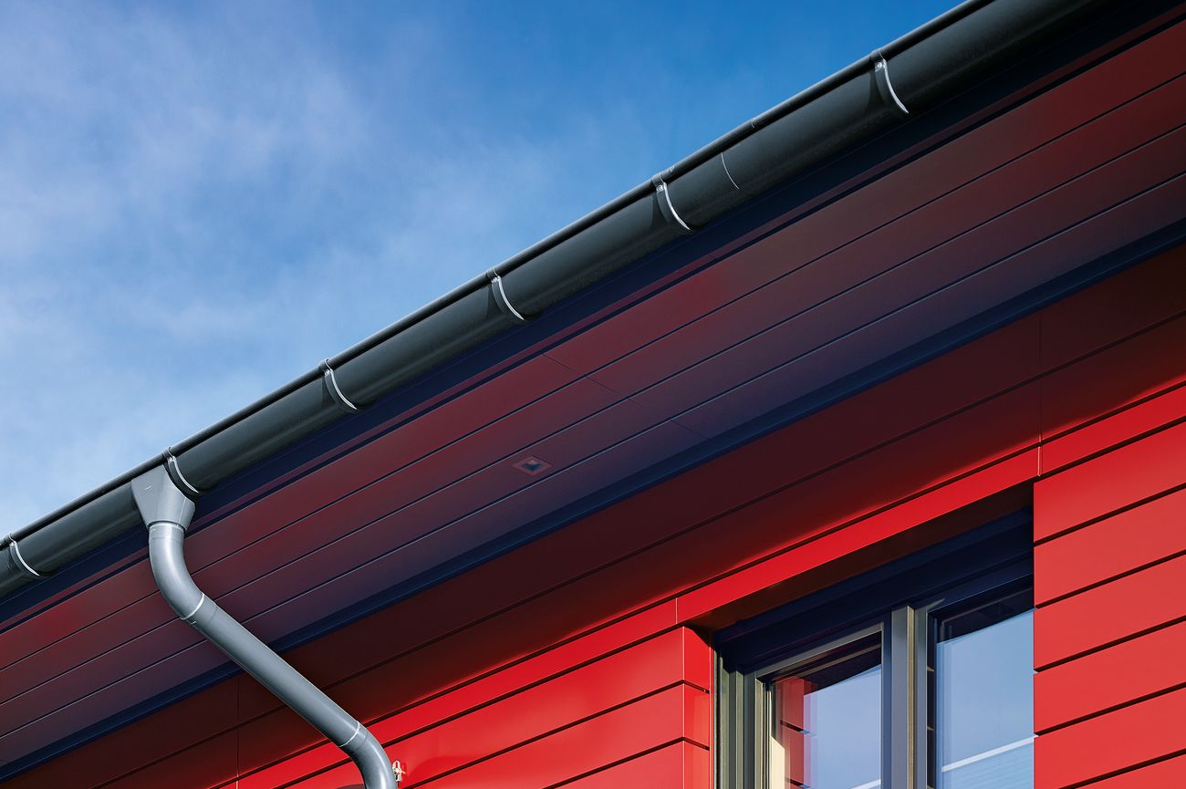 Dachentwässerung in schiefergrau vor roter Fassade